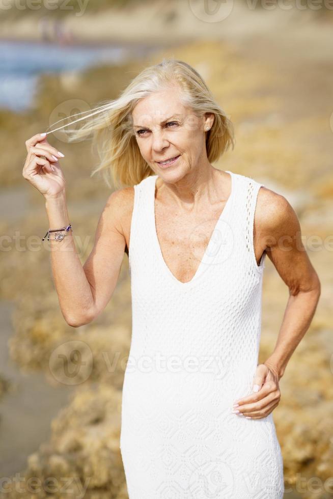 mujer madura caminando por la playa. anciana de pie en un lugar junto al mar foto