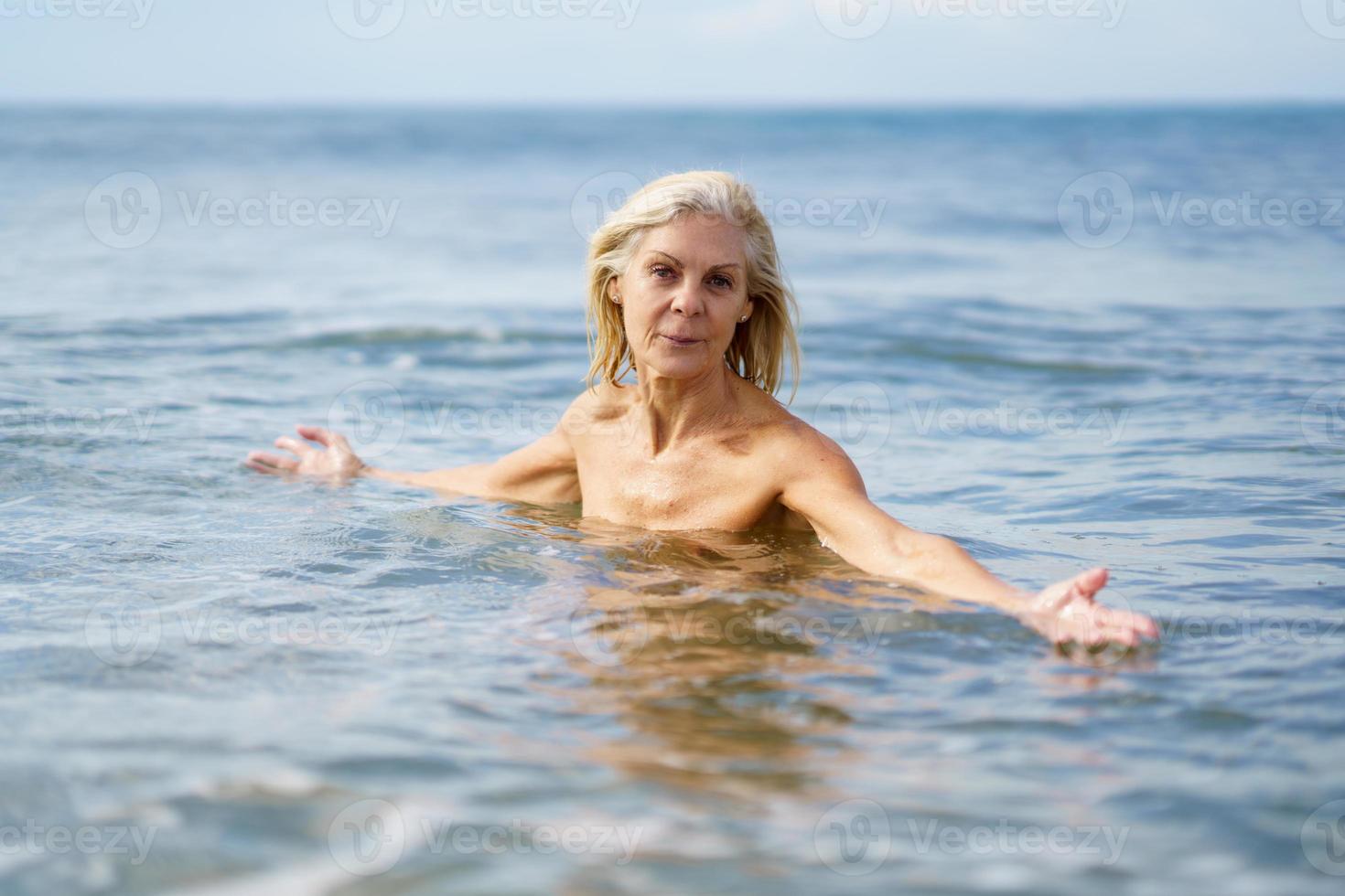 mujer madura en buena forma bañándose en el mar. foto