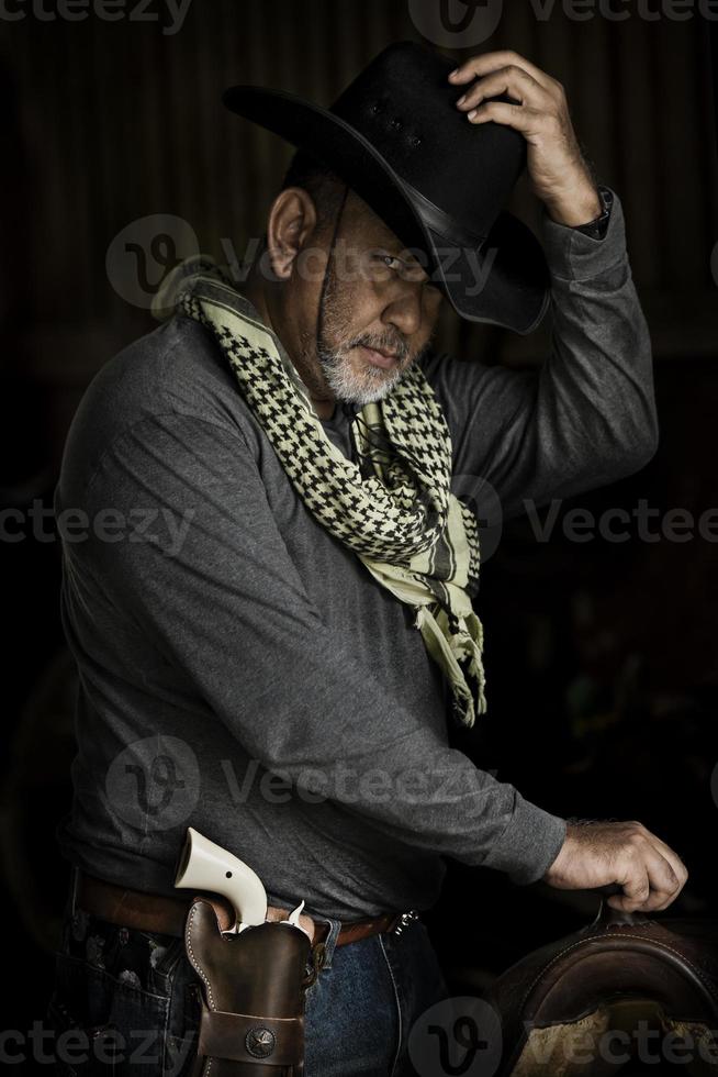 Brave cowboy Handsome old man looking at camera while standing against dark background photo