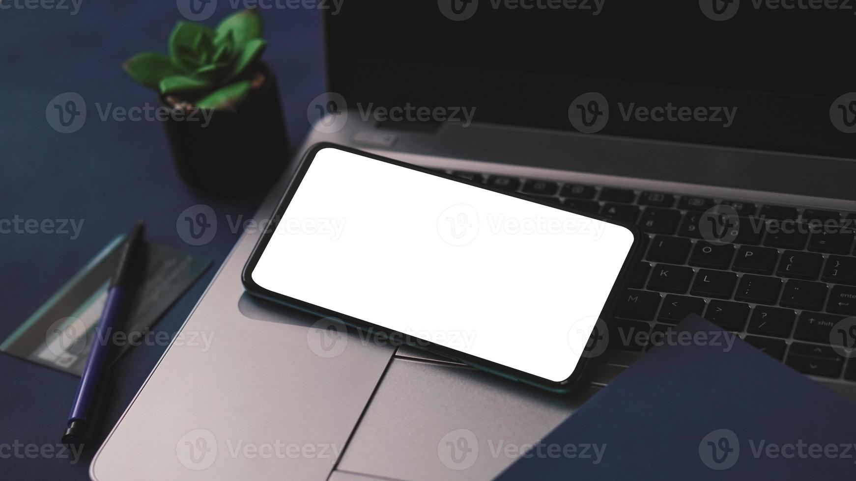 Mobile phone mockup template with white screen on a laptop for remote working and home office concept photo