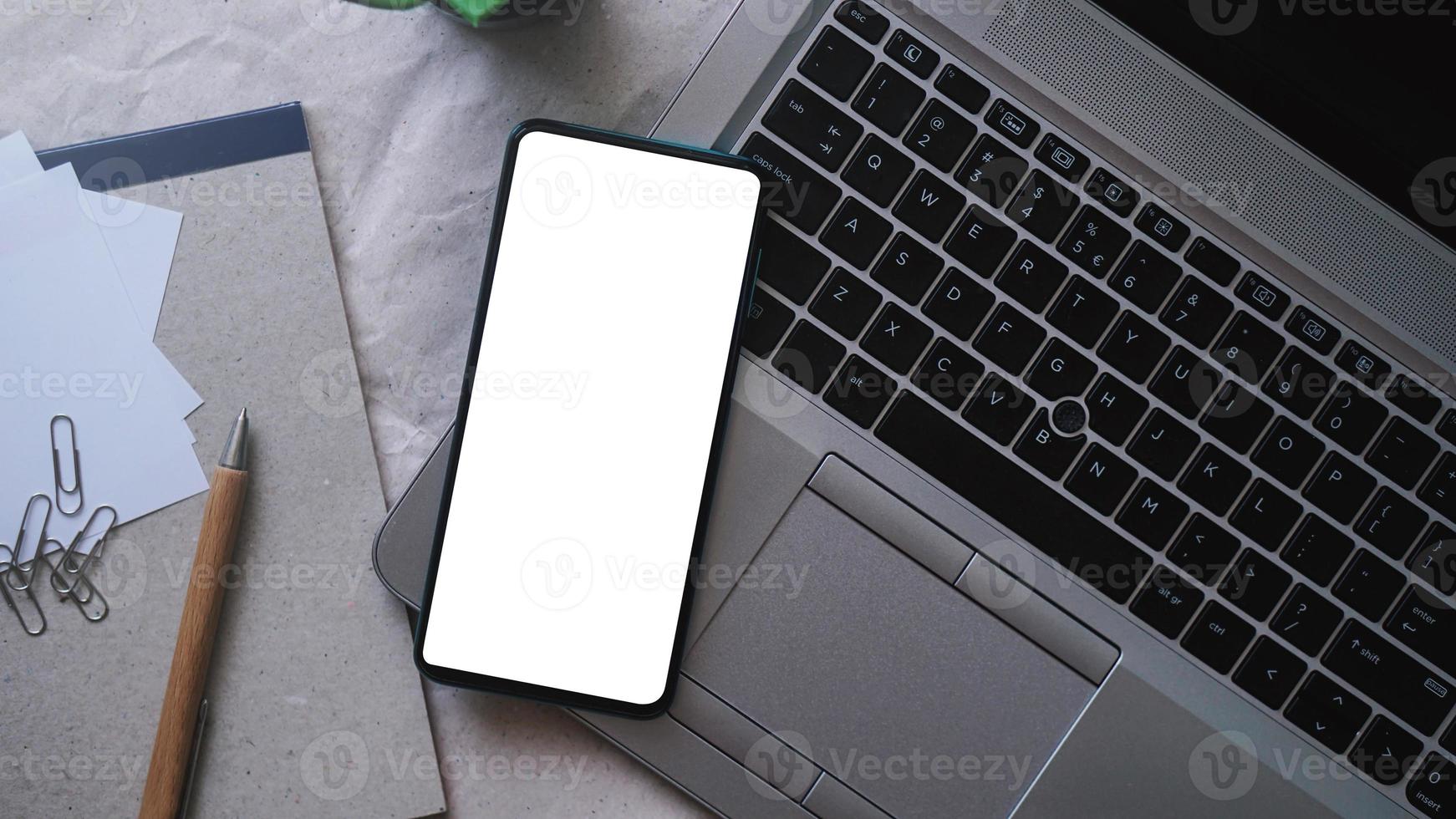 Mobile phone mockup template with white screen on a laptop for remote working and home office concept photo