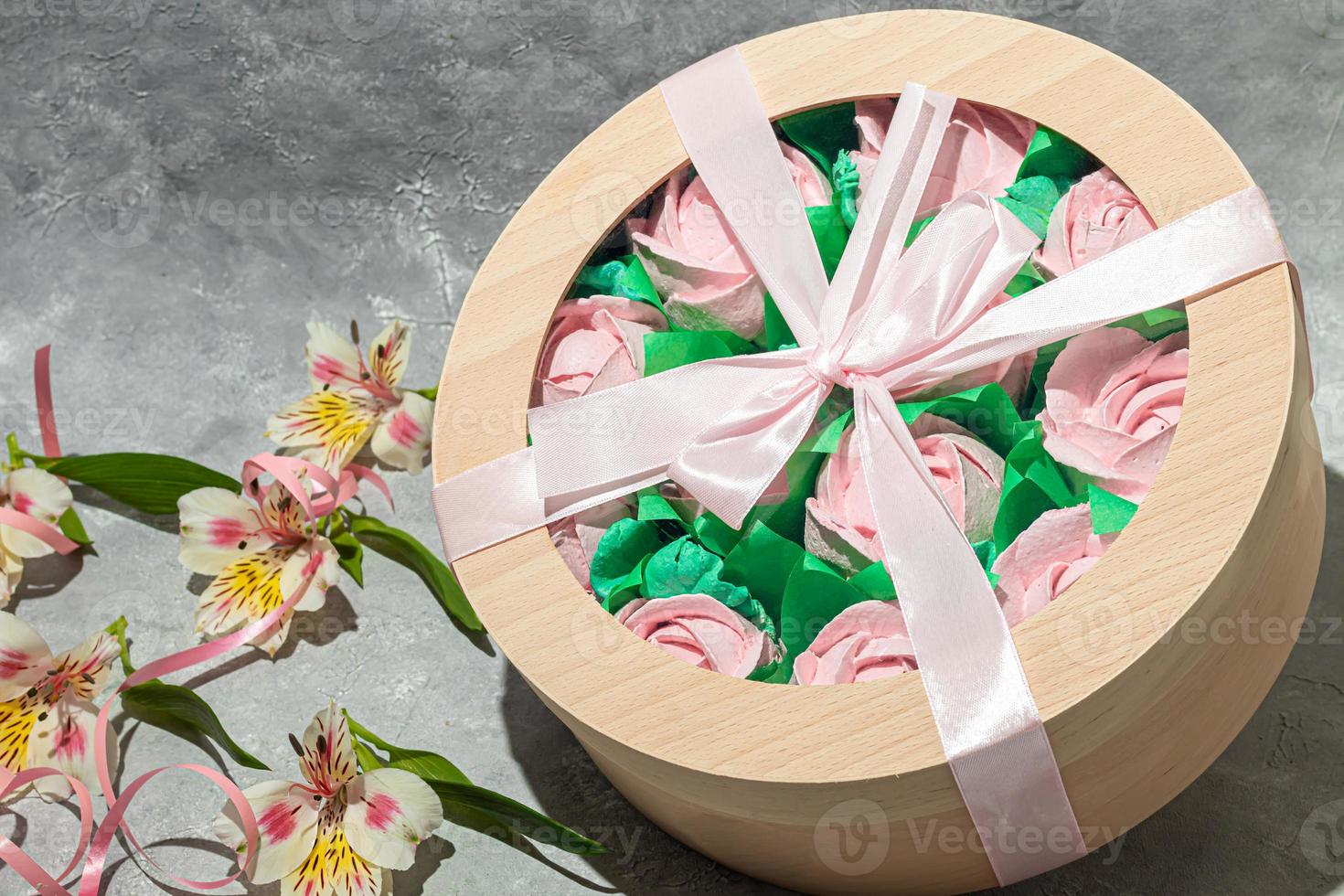 Handmade marshmallows in wooden packages on a light background with flowers. The concept of the holidays Women's Day and Valentine's Day. photo