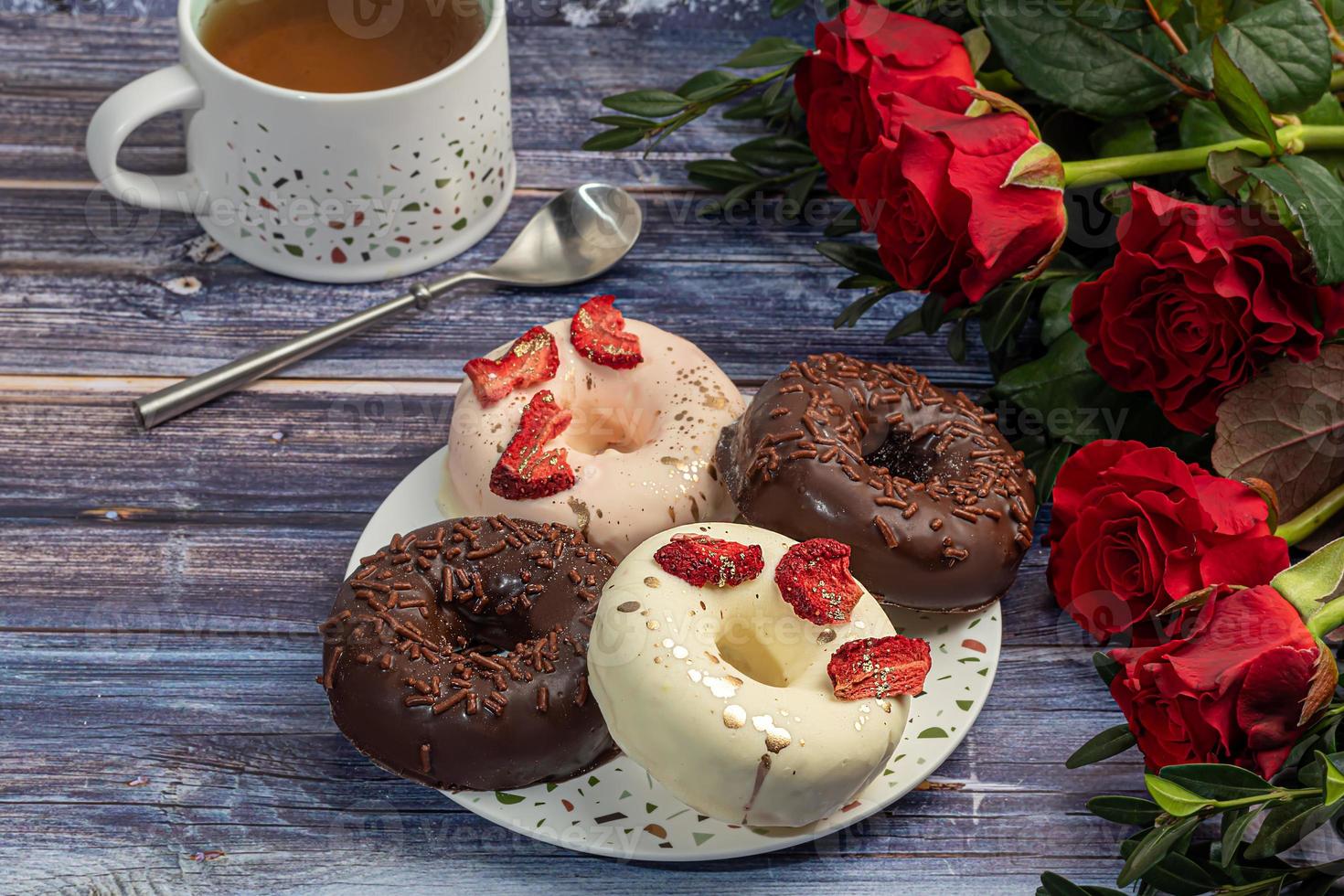 Handmade donuts on a light background in white and black chocolate. There are flowers nearby. Women's day, Valentine's day. photo