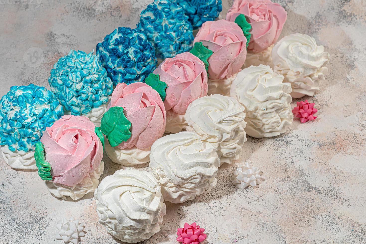 Handmade marshmallows on a light background in the form of roses, hydrangeas and tulips. There are flowers nearby. Women's day, Valentine's day. photo