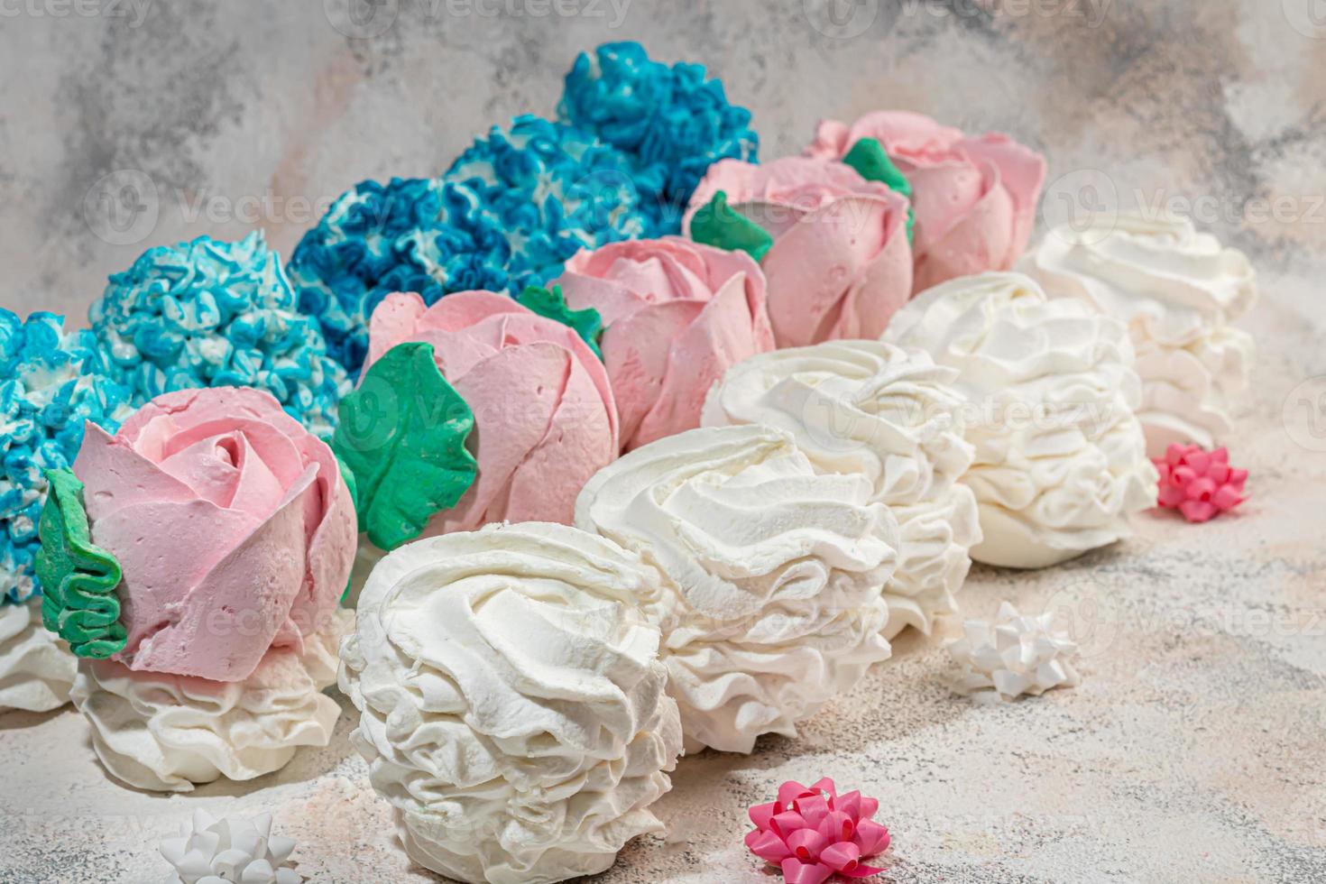 Handmade marshmallows on a light background in the form of roses, hydrangeas and tulips. There are flowers nearby. Women's day, Valentine's day. photo