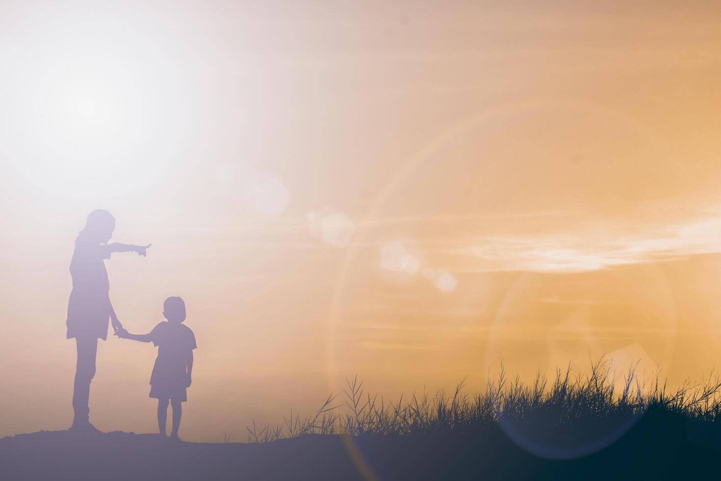 silueta madre e hijo al atardecer, apuntando al sol foto