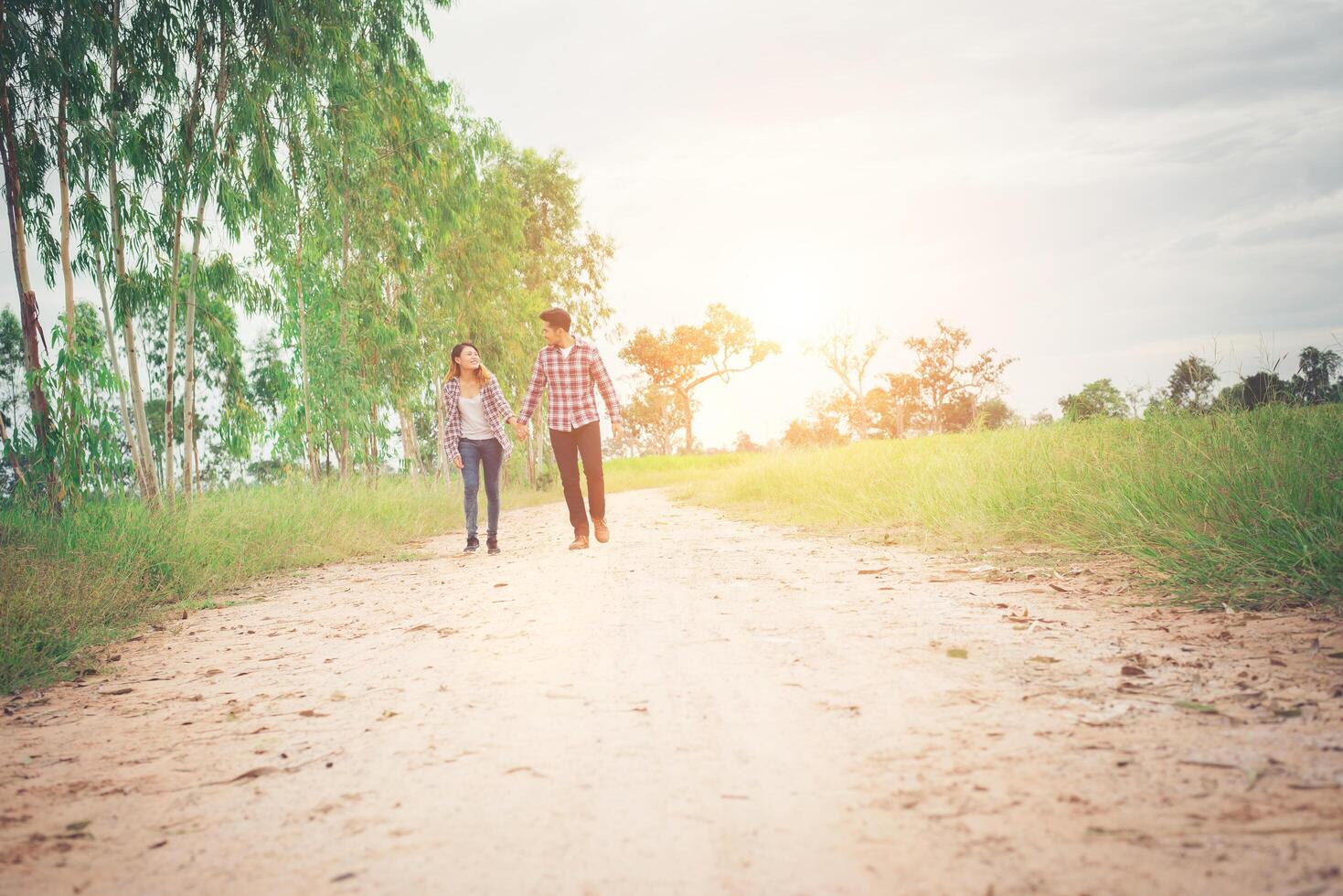 pareja joven hipster caminando por caminos rurales disfrutando de la naturaleza, pareja de amor, viajes de vacaciones, pasar tiempo juntos. foto