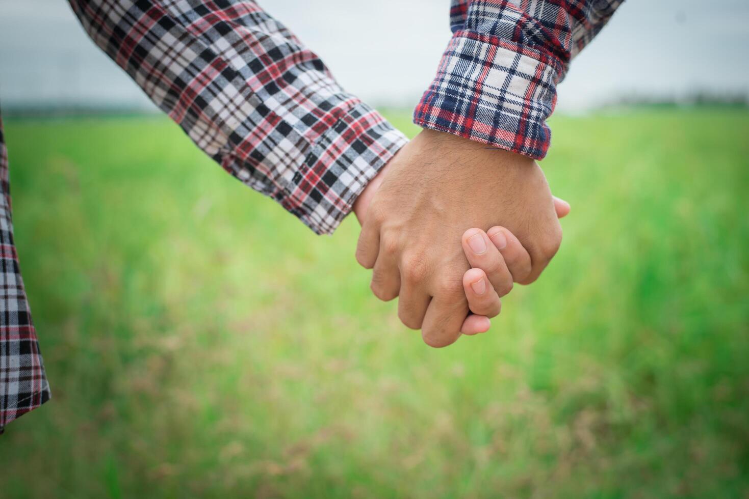 Close Up of loving hipster couple holding hands while walking at meadows field. photo