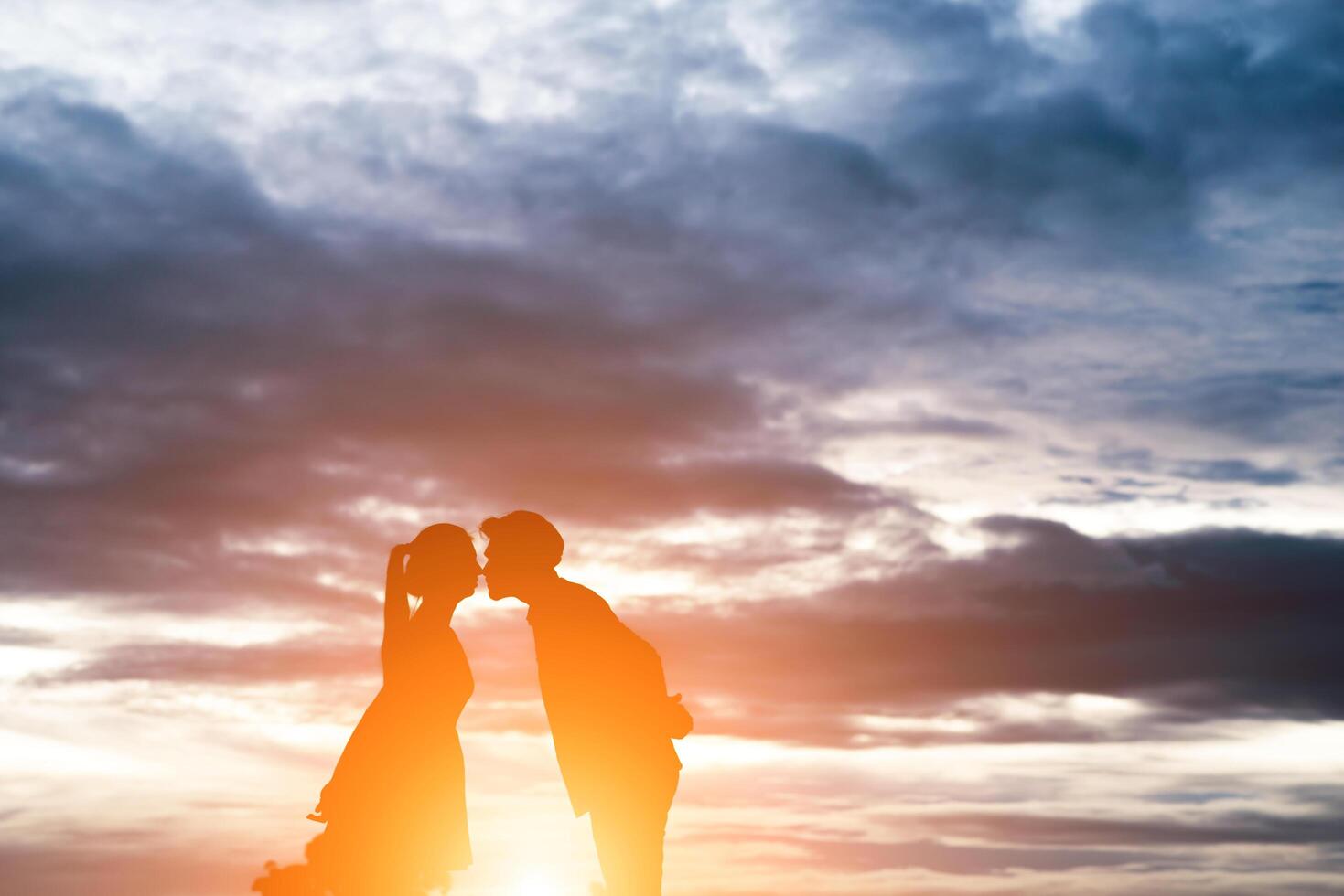 Silhouette of sweet couple kissing over sunset background. photo