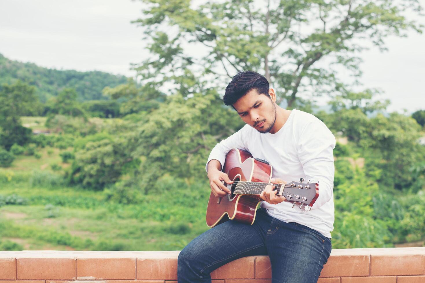 Young hipster man playing guitar to relaxing on his holiday, enjoy with natural and fresh air. photo