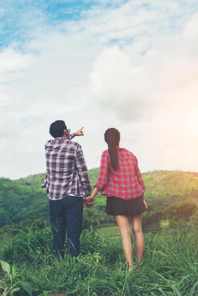 Young hipster couple holding hands walking on the meadow relaxing and natural atmosphere is very natural. photo