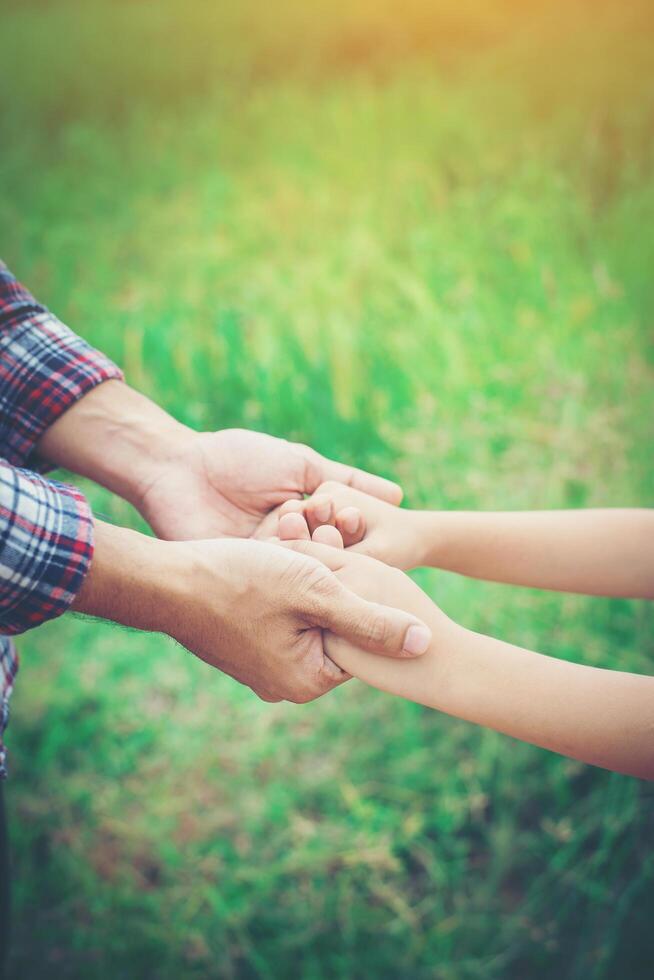 primer plano del padre sosteniendo la mano de su hija, tan dulce, tiempo en familia. foto