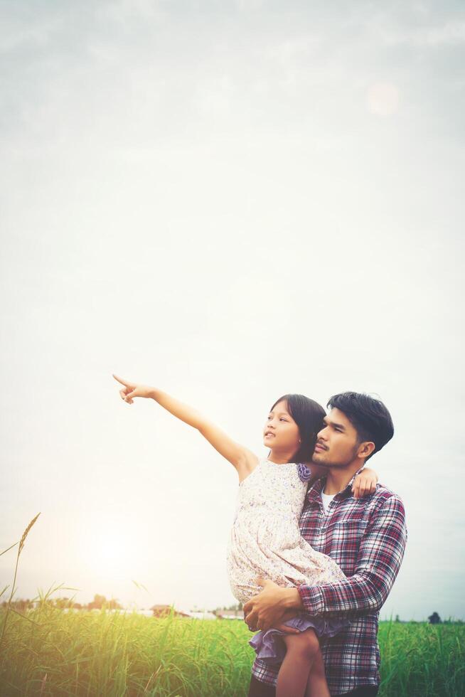 Daughter pointing away and smiling with her dad in the meadows field. photo