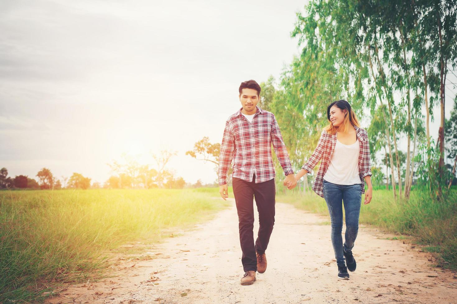 pareja joven hipster caminando por caminos rurales disfrutando de la naturaleza, pareja de amor, viajes de vacaciones, pasar tiempo juntos. foto