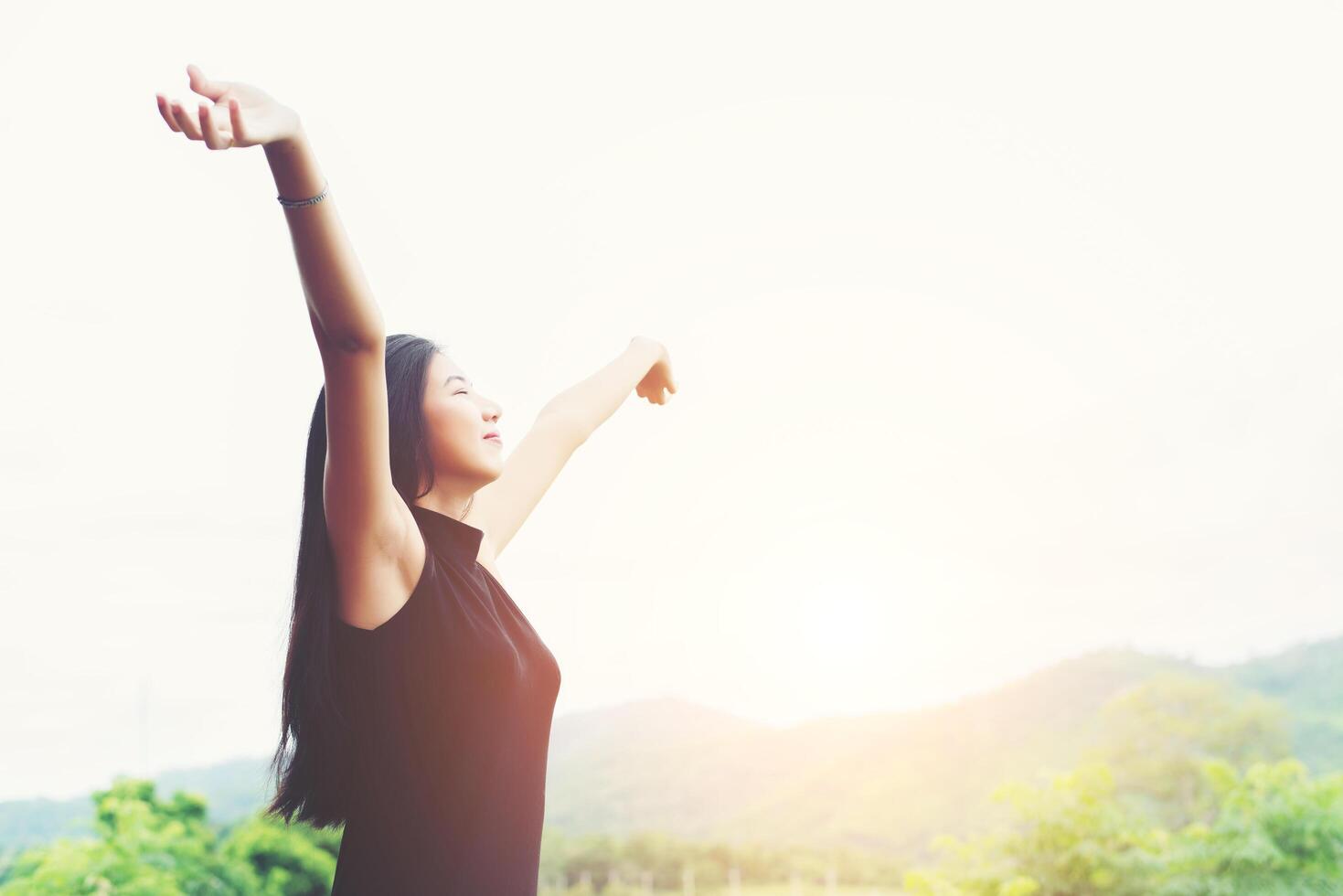 Young beautiful asian woman standing raising hands to relaxing with natural look at mountain. photo