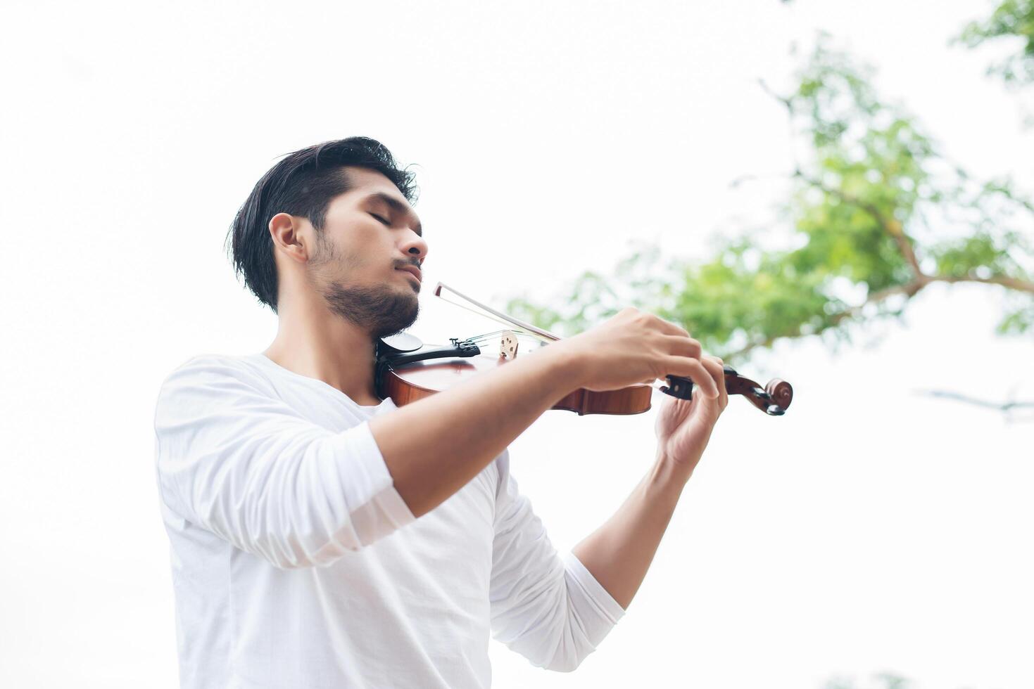 Young hipster musician man play violin in the nature outdoor lifestyle behind mountain. photo