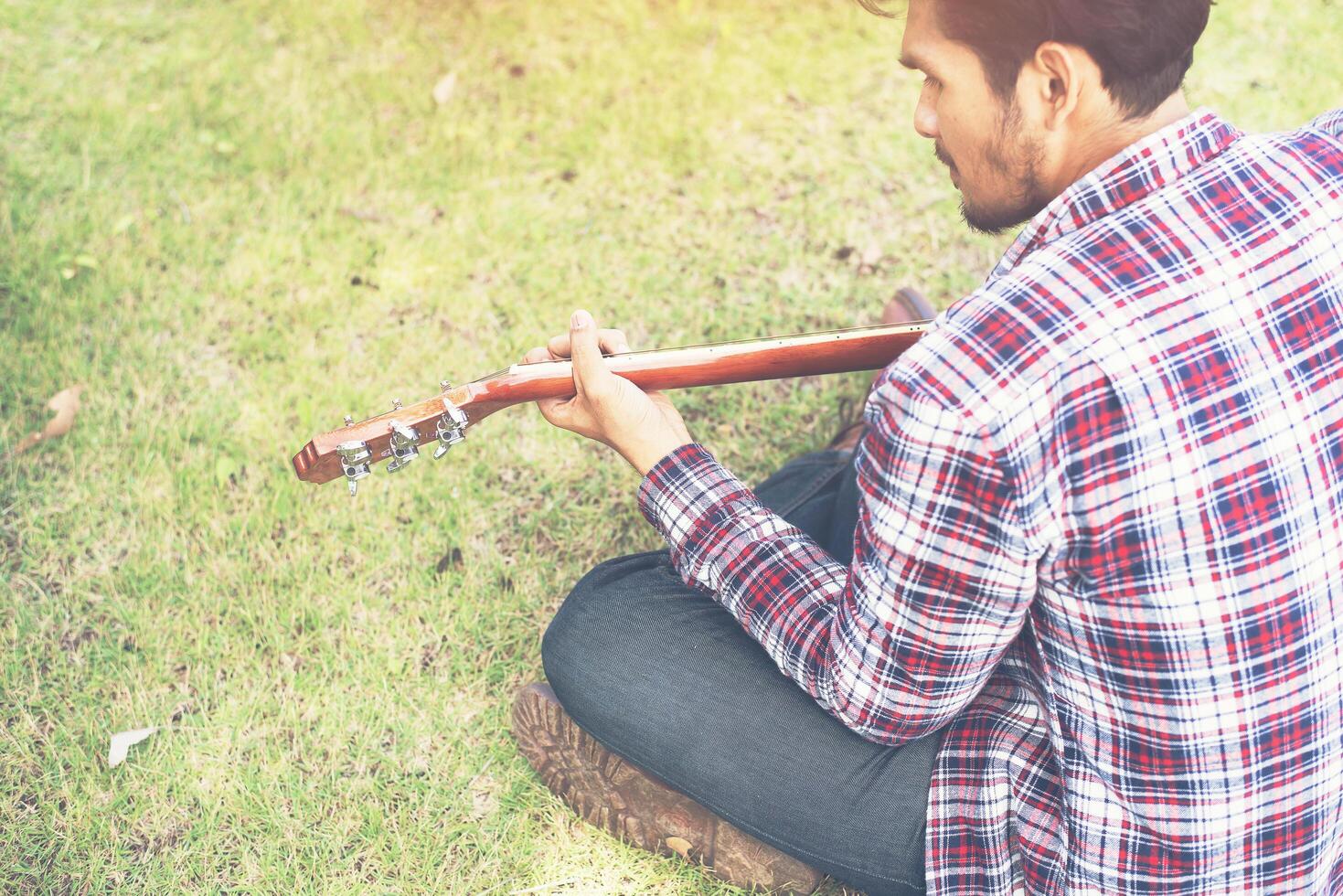 Young hipster man practiced guitar in the park,happy and enjoy playing guitar. photo