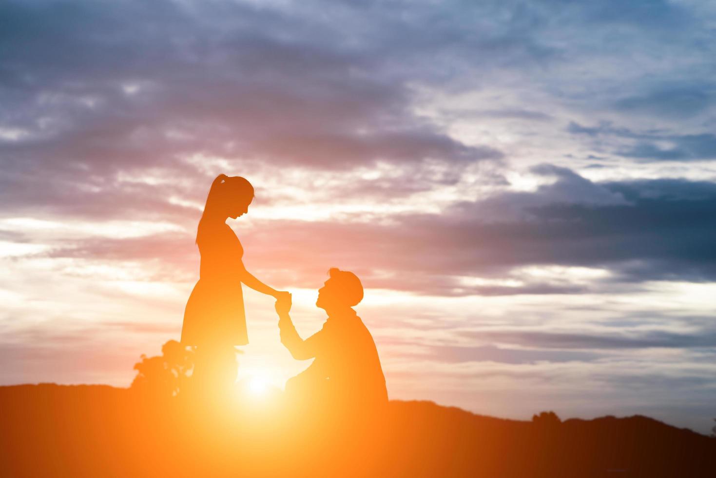 silhouette of man ask woman to marry on  mountain background. photo