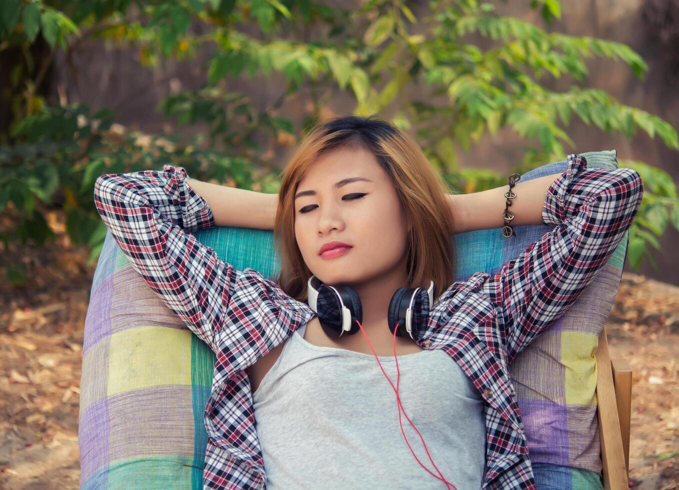 Young hipster woman relaxing in long chair with headphones on. photo