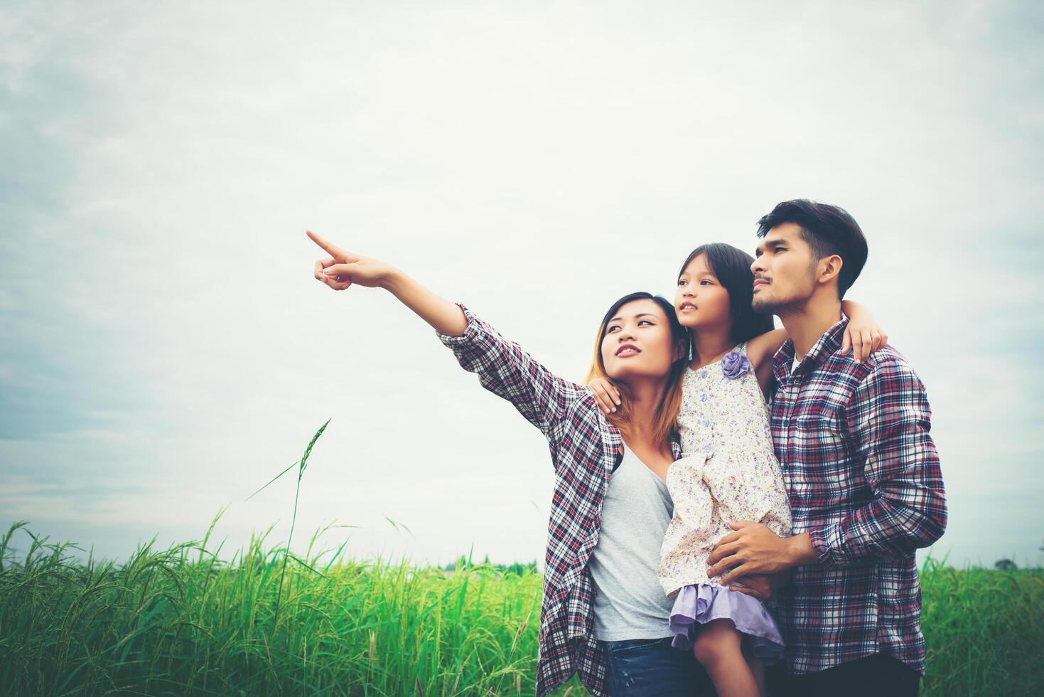 familia de madre, padre e hijo en el prado, papá cargando a la hija. foto