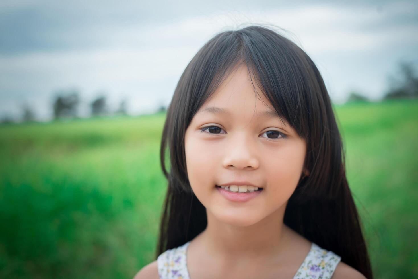 Close up of sweet little girl outdoors with smiling in the summer field. photo