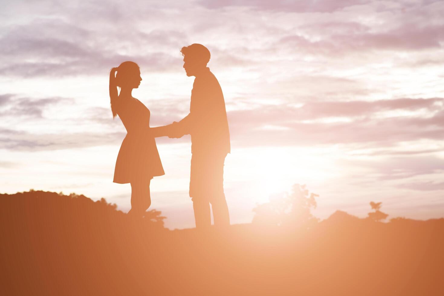 Silhouette of Young couple holding hands with mountain sunset background. photo