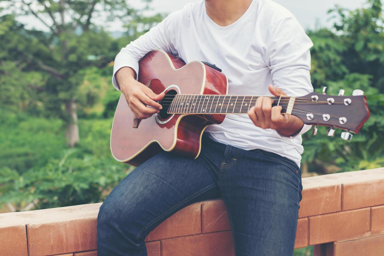 Young hipster man playing guitar to relaxing on his holiday, enjoy with natural and fresh air. photo