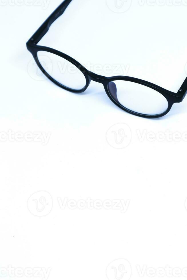 Oblique Top Shot of Black Eyeglasses in The Corner of Minimalist White Background, Portrait Mode photo