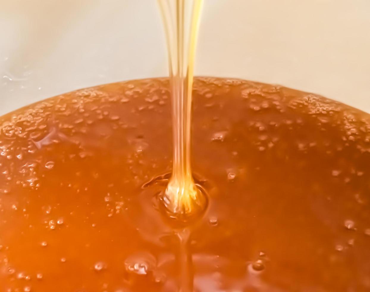 Drop of bee honey drip from hexagonal honeycombs photo