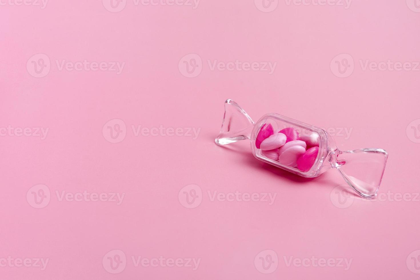 Transparent box in the shape of a candy with sweet heart lollipops on a pink background copy space. Banner photo