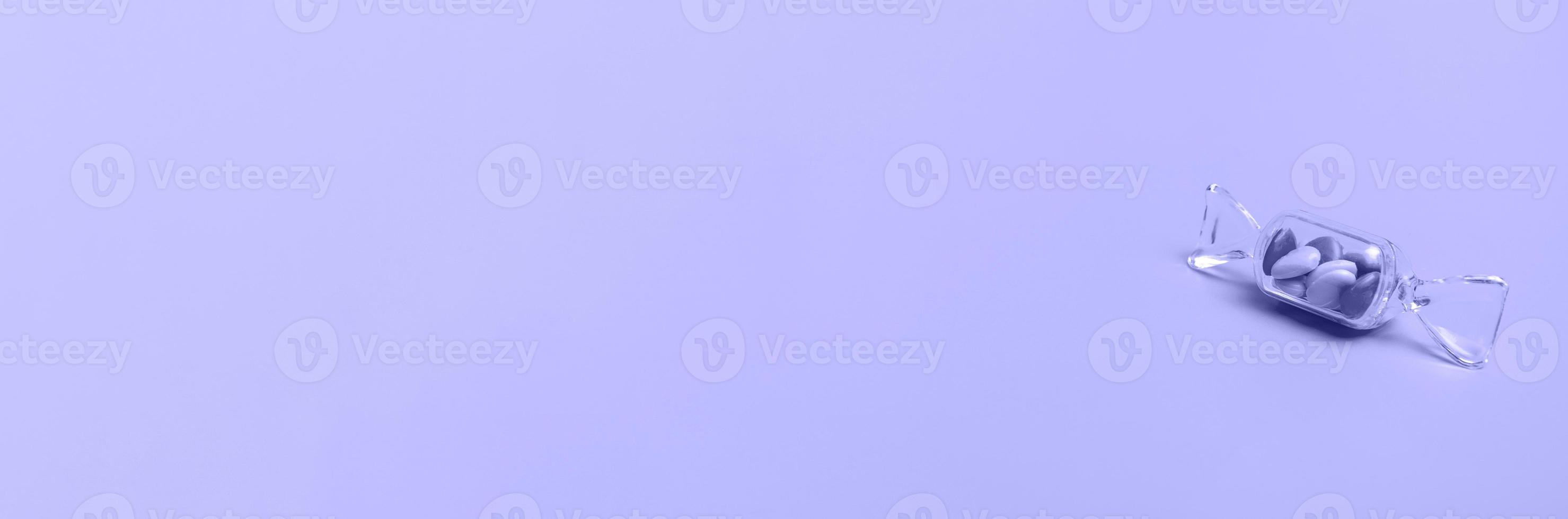 Transparent box in the shape of a candy with sweet heart lollipops on a very peri background copy space. Banner photo
