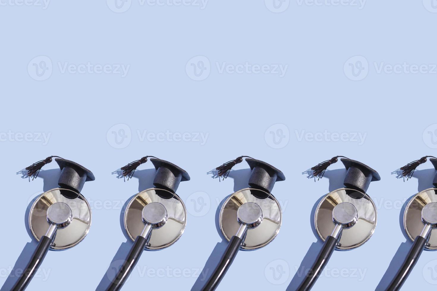 Stethoscope and graduation cap with hard shadow on blue background. Medical education concept, closeup with copy space photo