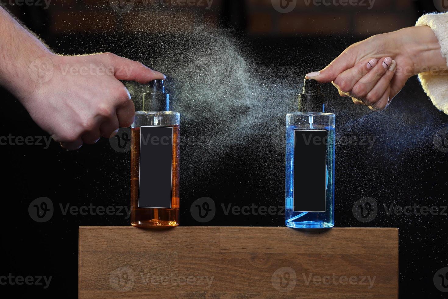 las manos de un hombre y una mujer rocían una loción para el cabello coloreada. dos latas de aerosol sobre fondo negro en soporte de madera. copie el espacio en latas, frascos. enfoque selectivo. barbería foto