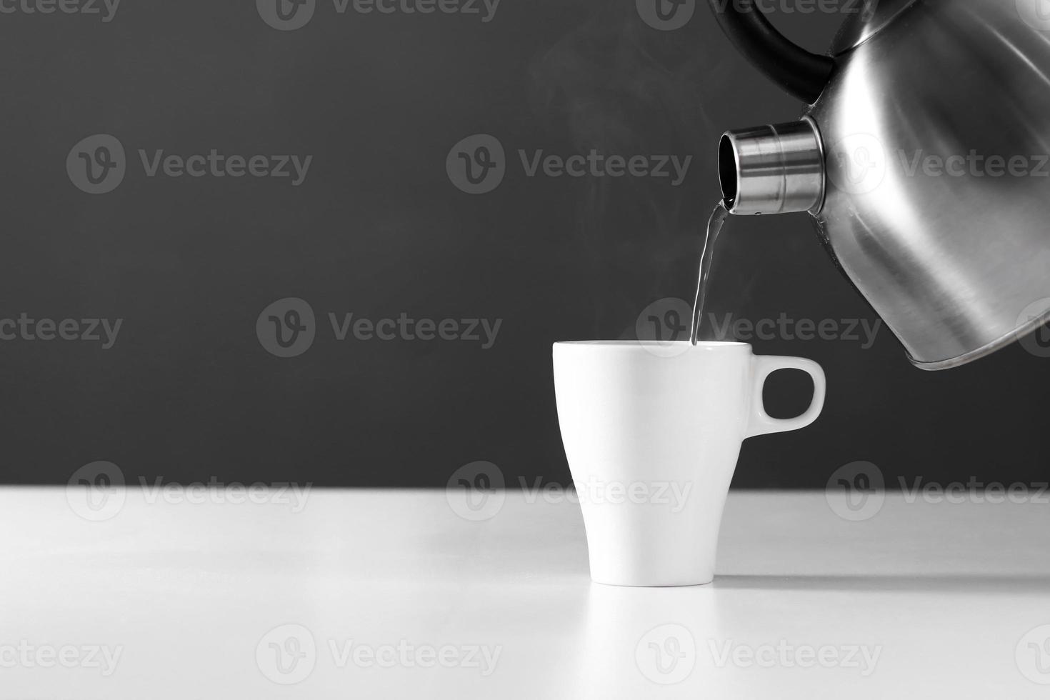 retro kettle pouring water into a cup on a dark background with smoke on wood table photo