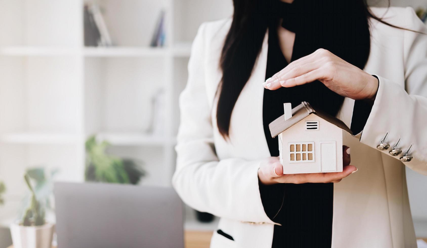 Close up of businessman holding model house. Architecture, building, construction, real estate and property concept photo