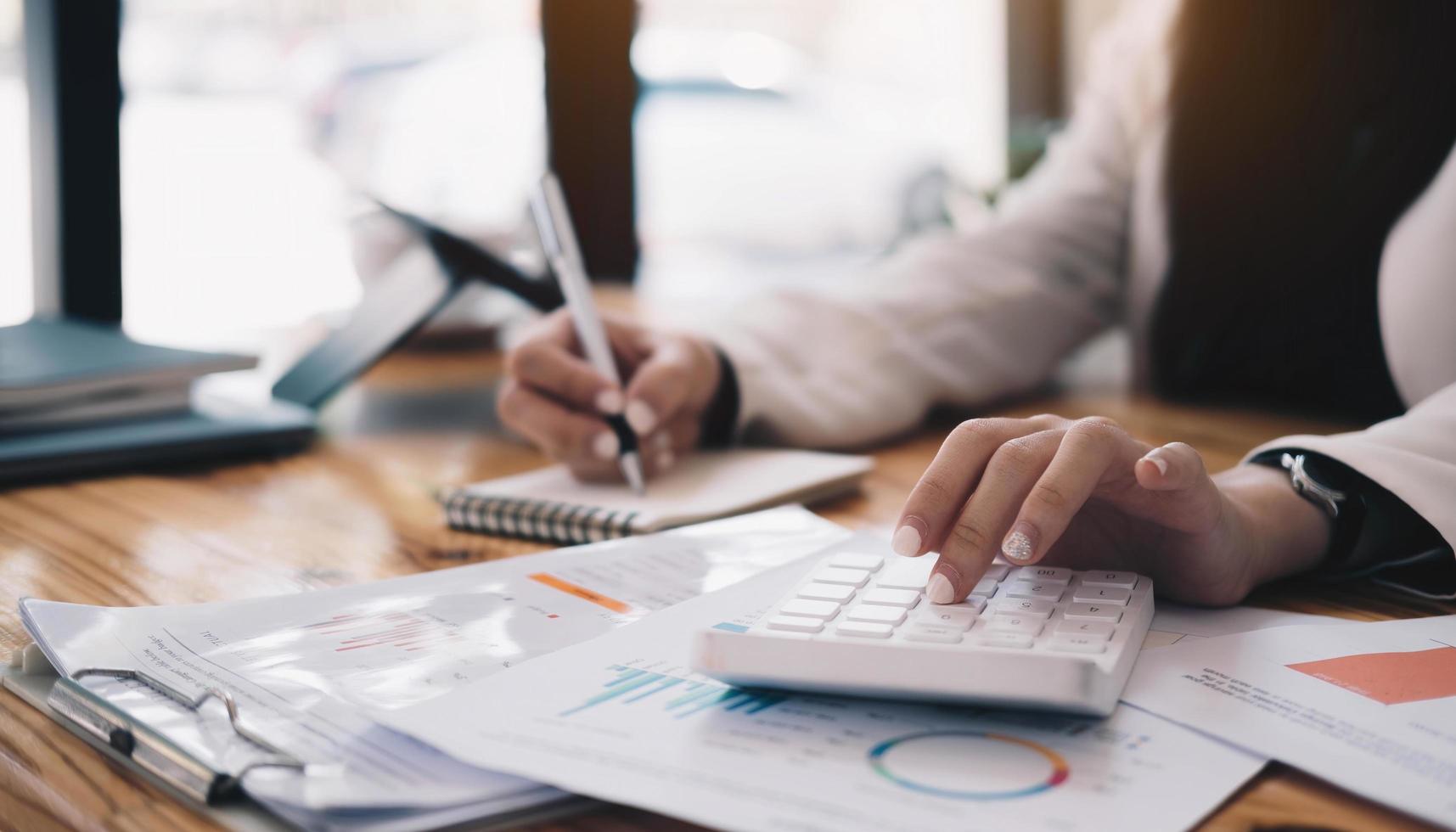 Close up Business woman using calculator and write on paper photo