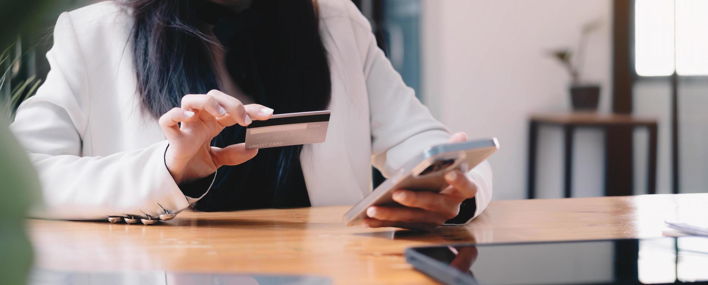 A wonan holding credit card and typing in credit card number smartphone for online shopping and payment makes a purchase on the Internet. photo