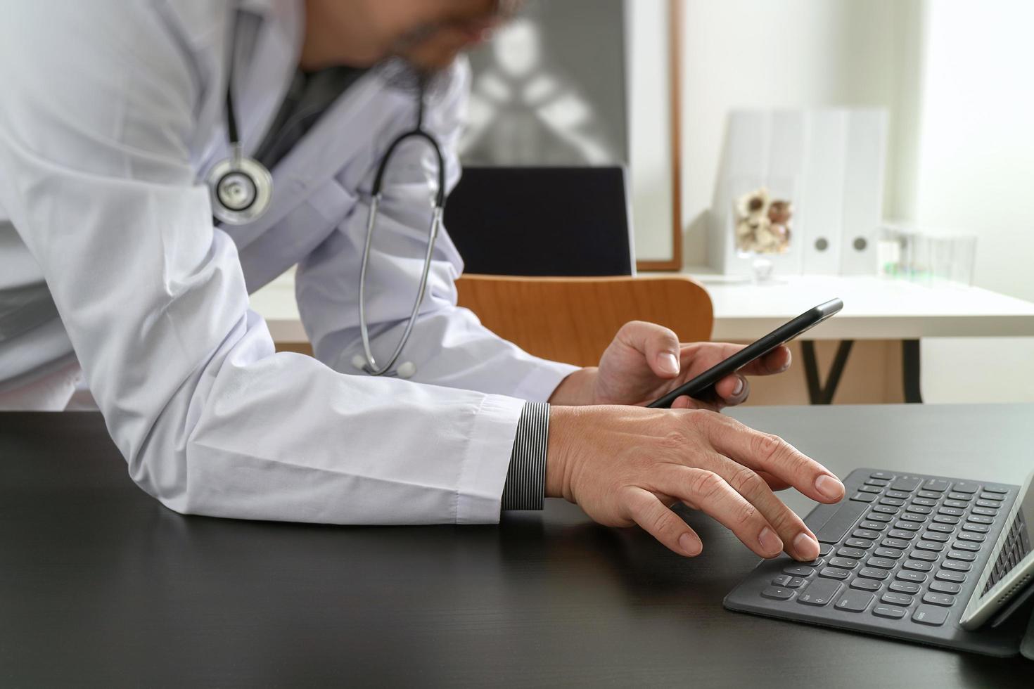 Medical technology concept. Doctor working with smart phone and stethoscope and digital tablet computer in modern office at hospital photo