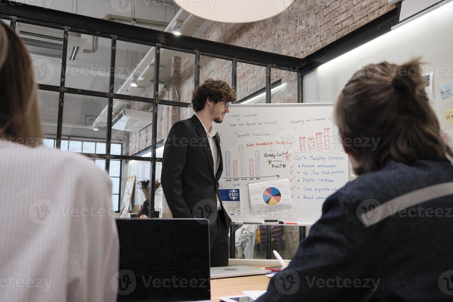 Coworkers' team and colleague brainstormed, discussing marketing strategy, ideas collaboration, and business project planning with a caucasian boss at office's conference, staff meeting workplace. photo