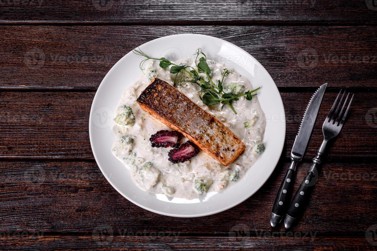 Tasty baked salmon fish on a white dish with broccoli and pea sprouts photo