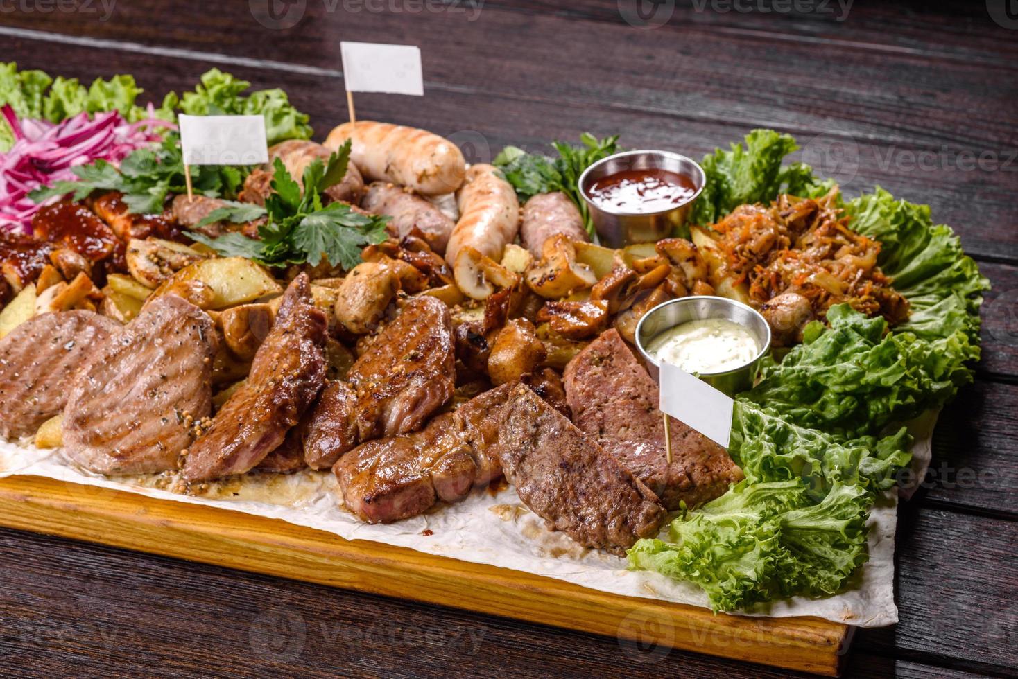 Several types of roasted meat with spices and herbs on a wooden tray photo