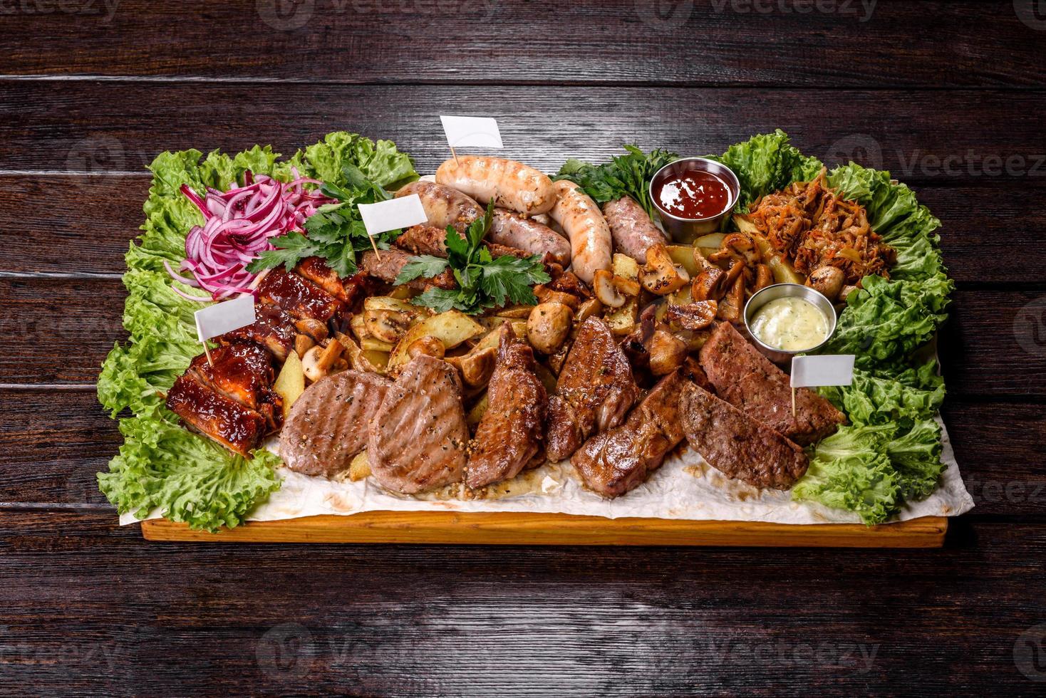 Several types of roasted meat with spices and herbs on a wooden tray photo