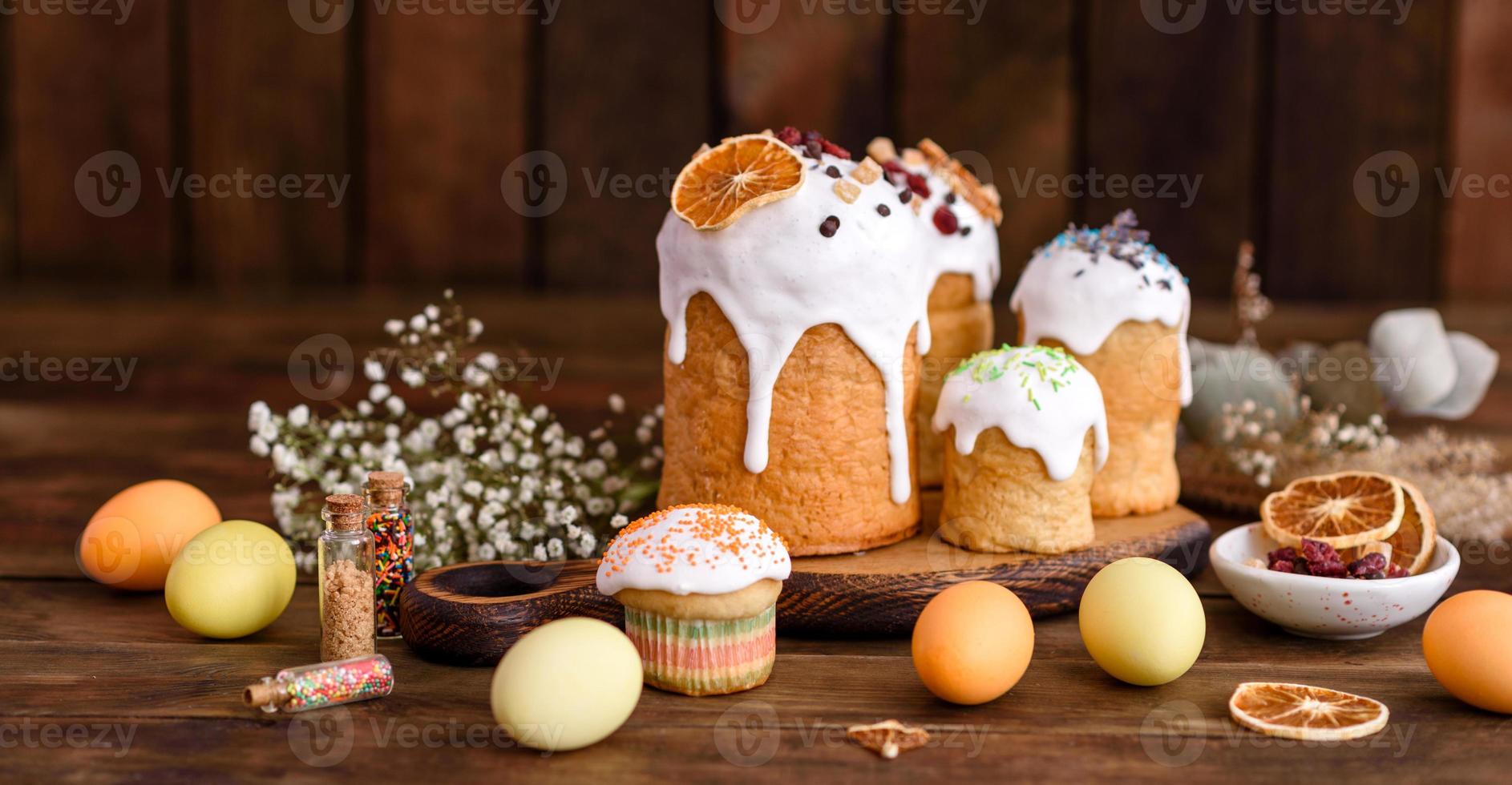 Easter holiday concept. Easter cakes , willow, painted eggs and candle on rustic wooden table photo