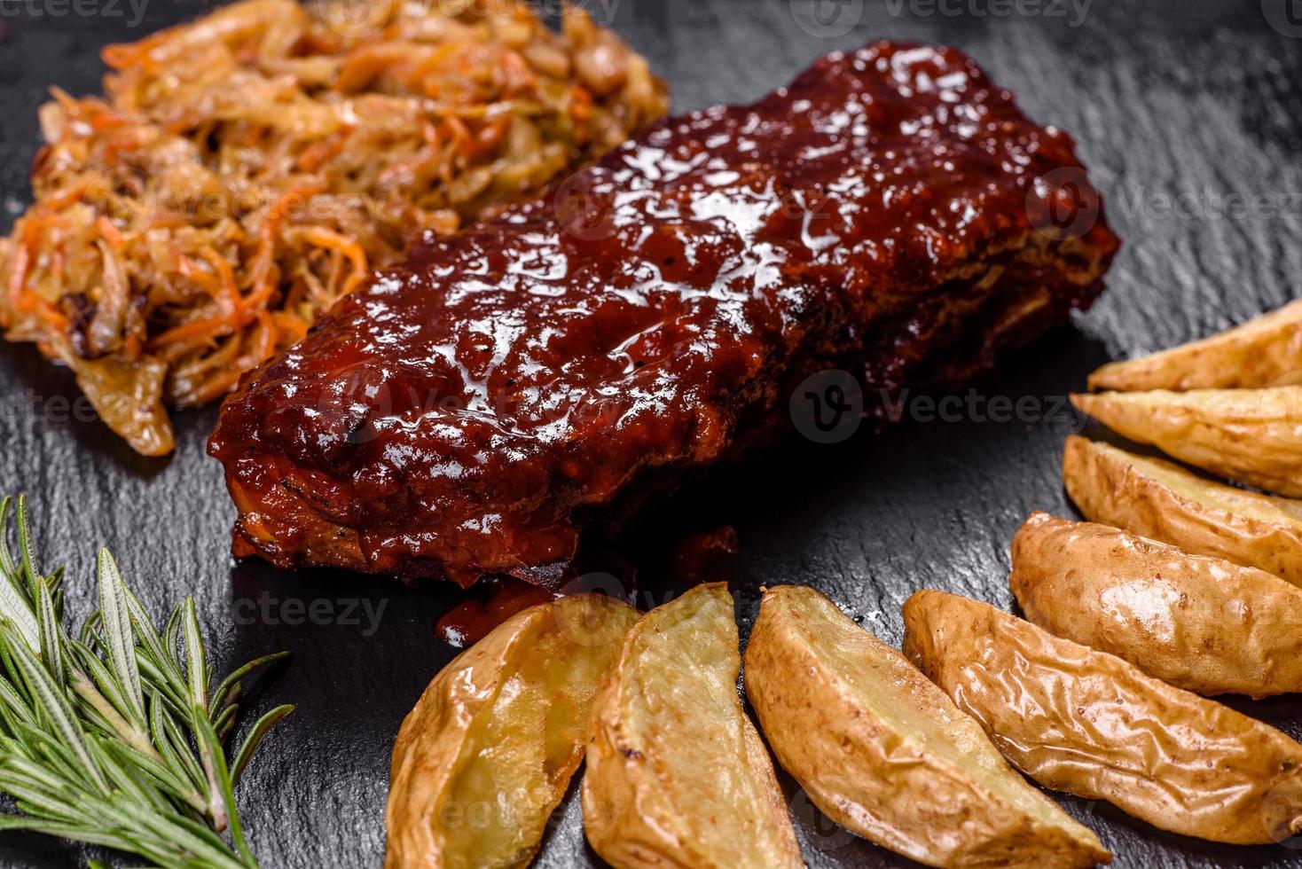 Spicy barbecued pork ribs served with BBQ sauce on chopping board photo