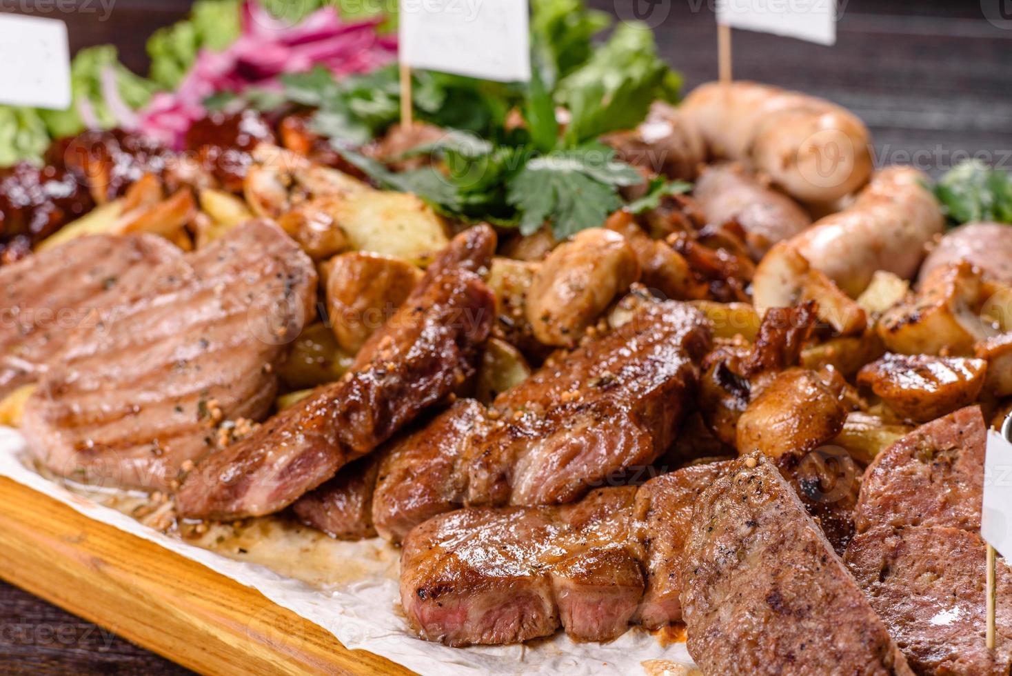 Several types of roasted meat with spices and herbs on a wooden tray photo