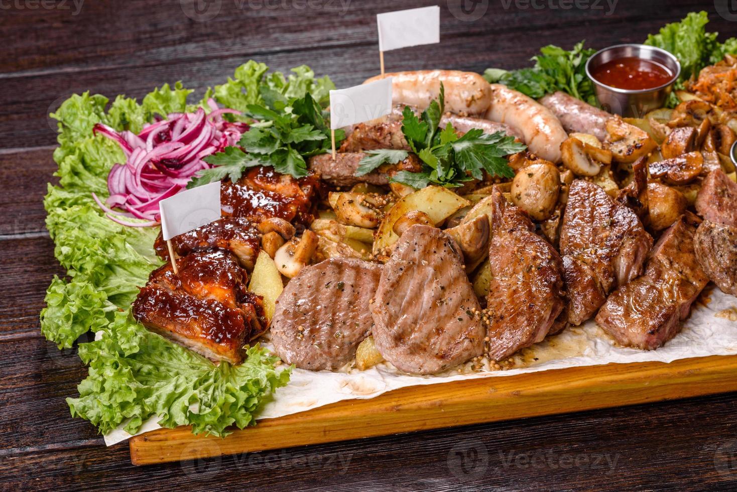 Several types of roasted meat with spices and herbs on a wooden tray photo