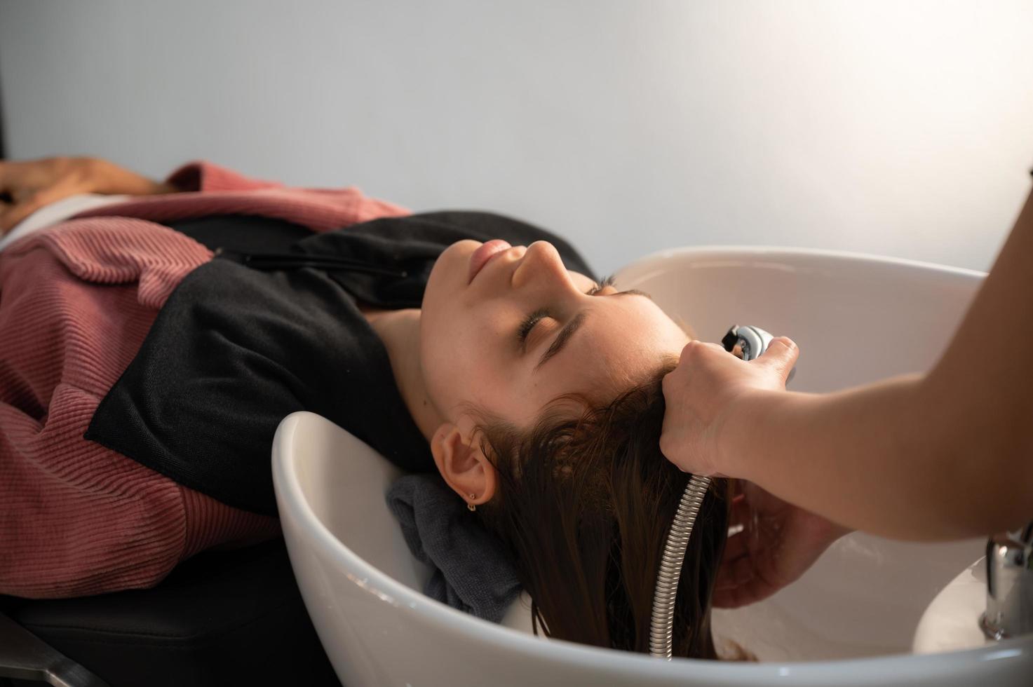 peluquera y hermosa mujer cliente haciendo tratamiento de salud del cabello en un salón de estilo de moda foto