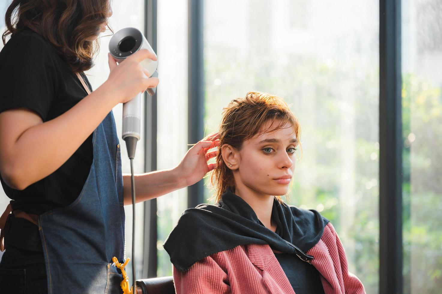 peluquera y hermosa mujer cliente haciendo tratamiento de salud del cabello en un salón de estilo de moda foto