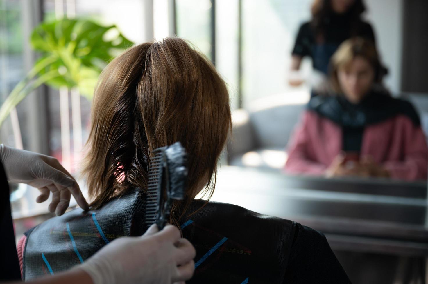 peluquera y hermosa mujer cliente haciendo tratamiento de salud del cabello en un salón de estilo de moda foto