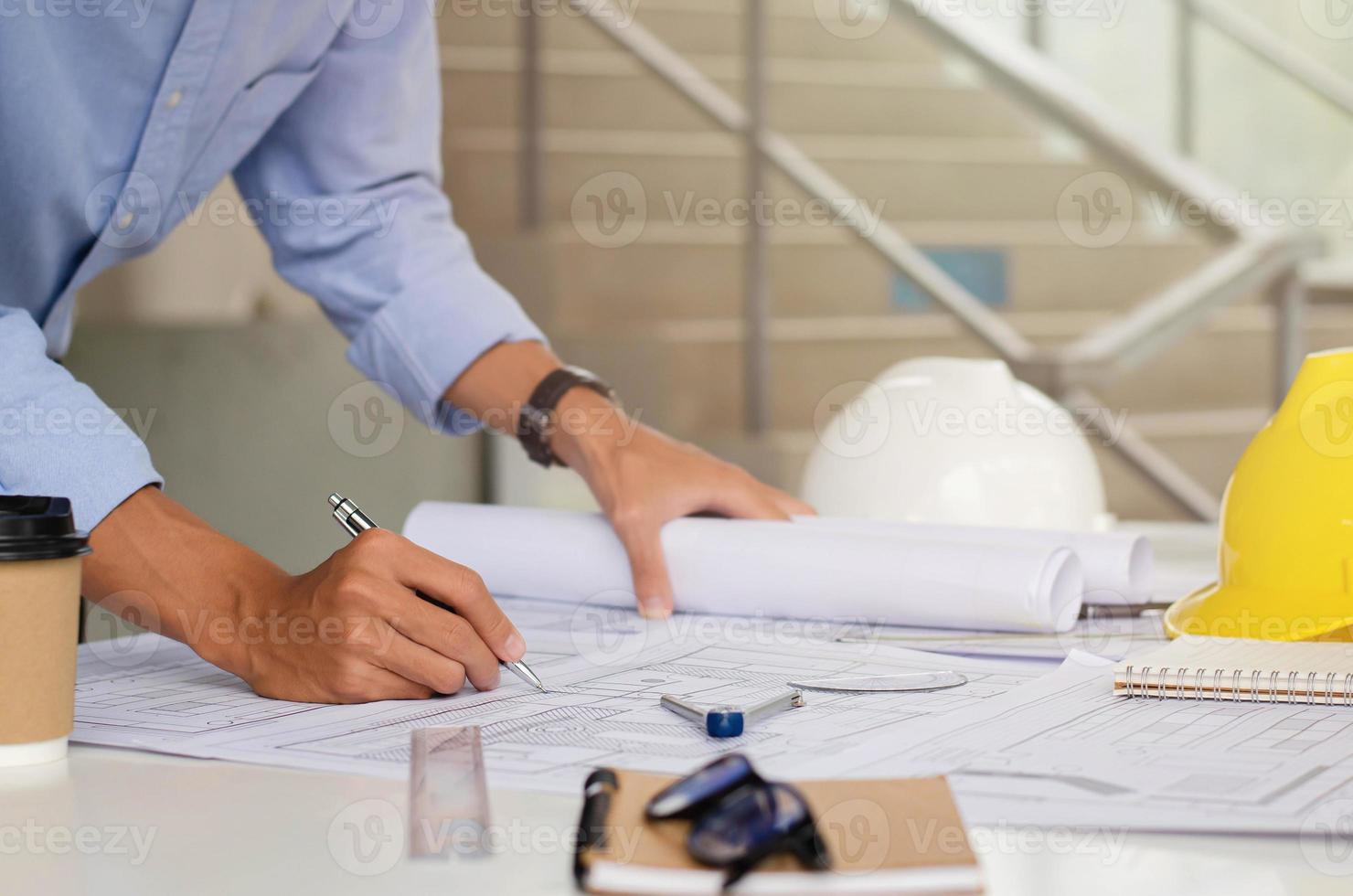 The engineer is drafting the planning structure. with architect equipment and architectural blueprints at the desk, coffee photo